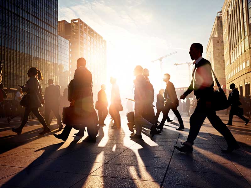 People walking around the street, with a sunset in the background